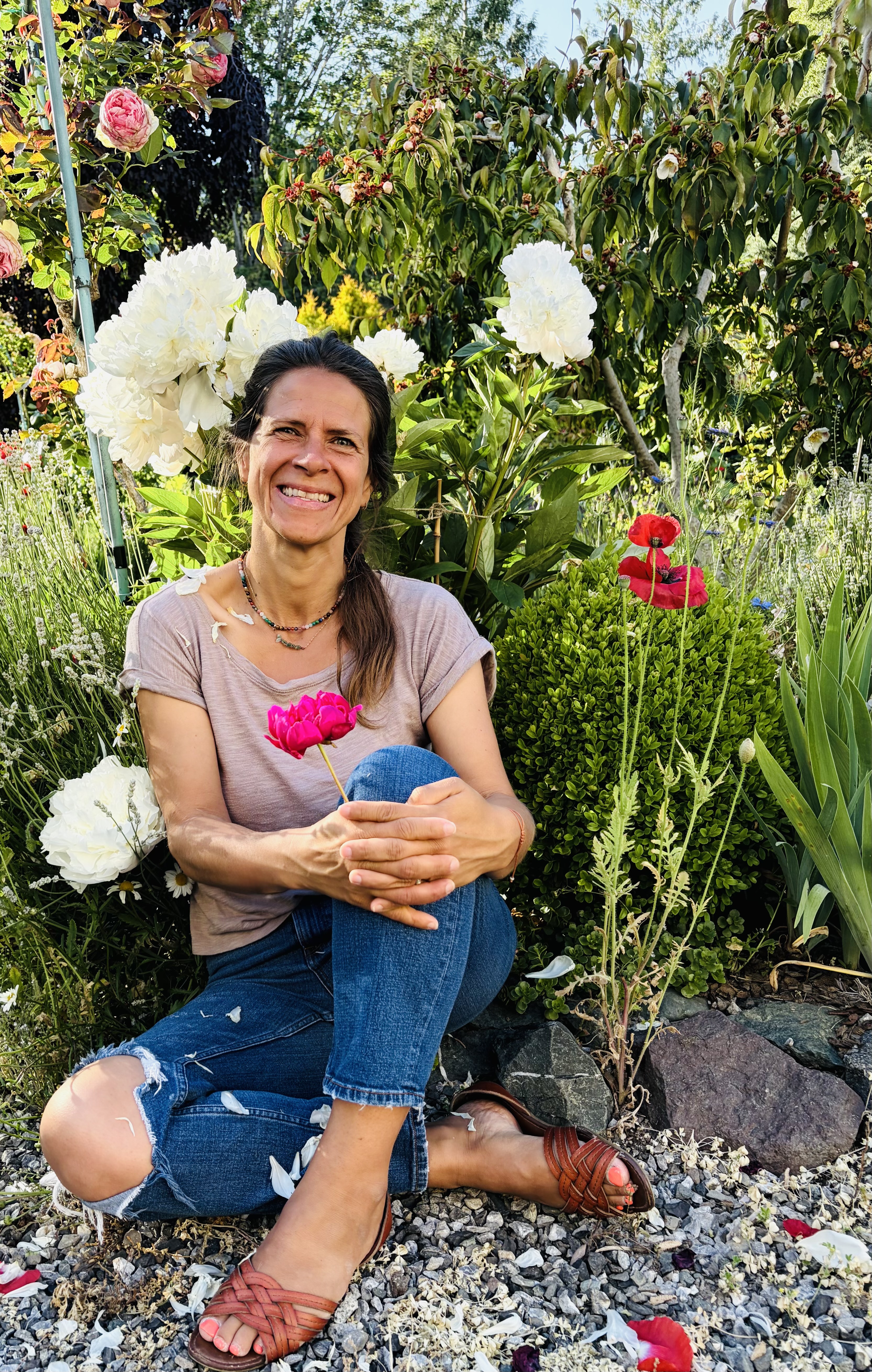 Andrea sitting in her garden surrounded by peonies
